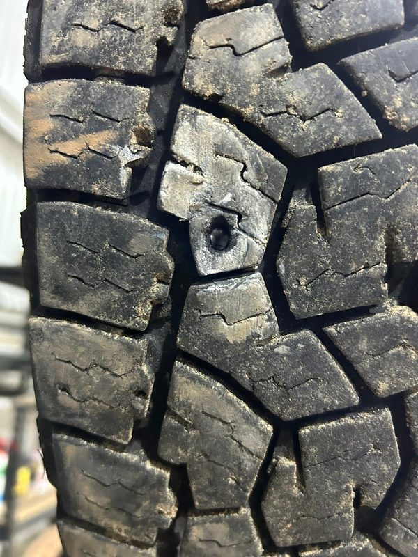 Close-up of an all-terrain tyre tread with a puncture hole