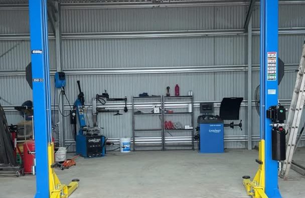 Workshop shed with a blue two-post car hoist, tyre changer and wheel balancer